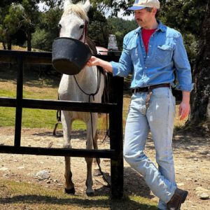 man in a cool pose feeding a horse