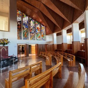 The interior of the church, often a highlight of a Bogota day tour, features wooden pews and vibrant stained glass windows depicting colorful scenes beneath an intricately designed wooden ceiling.